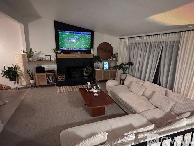 A living room with a fireplace and a television playing a football game.