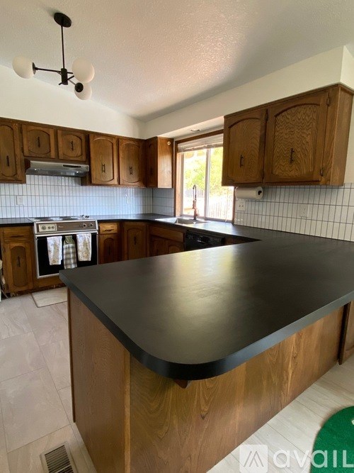 A kitchen with a black countertop and wooden cabinets.