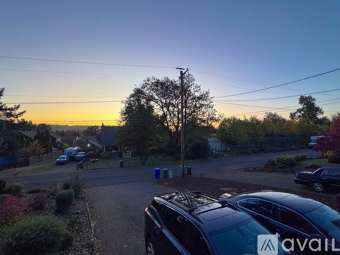 A car is parked on a street with a house and trees in the background.