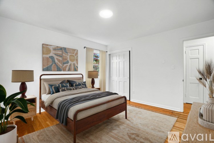 A bedroom with a bed, a lamp, a painting, and a rug.