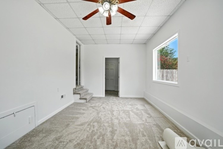 A room with a ceiling fan and carpeted floor.
