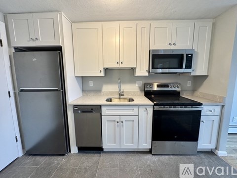 A kitchen with white cabinets and a black fridge.