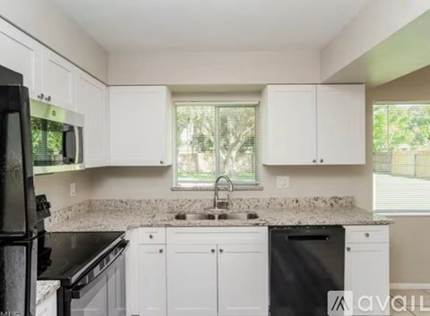 A kitchen with white cabinets and black appliances.