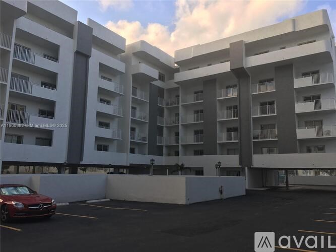 A car is parked in a parking lot in front of apartment buildings.