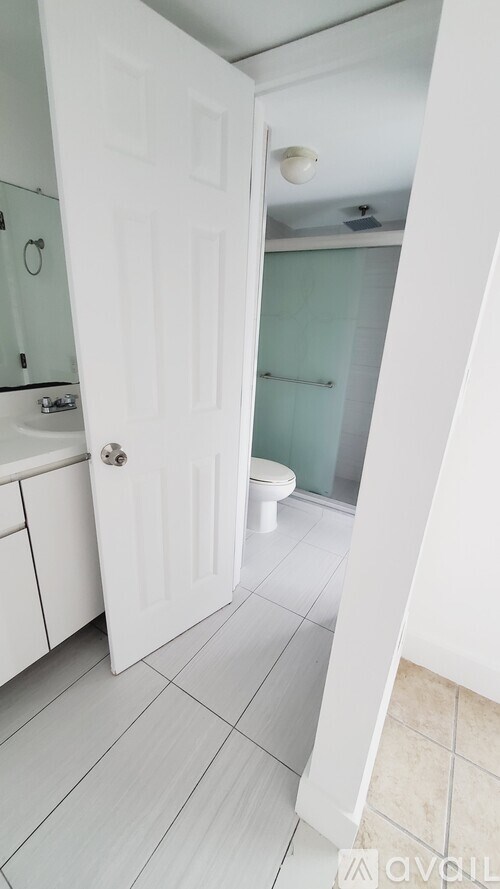 A white door is open to a bathroom with a toilet and shower.
