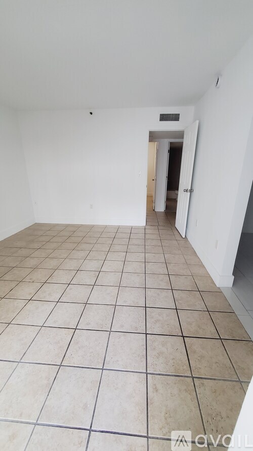 A room with white walls and tiled flooring with a doorway in the background.