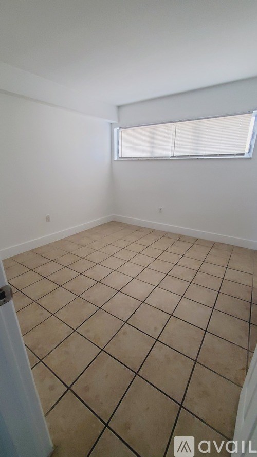 A room with a tiled floor and a window with blinds.