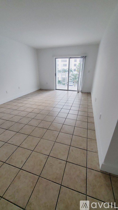 A room with tiled flooring and a doorway leading to a balcony.