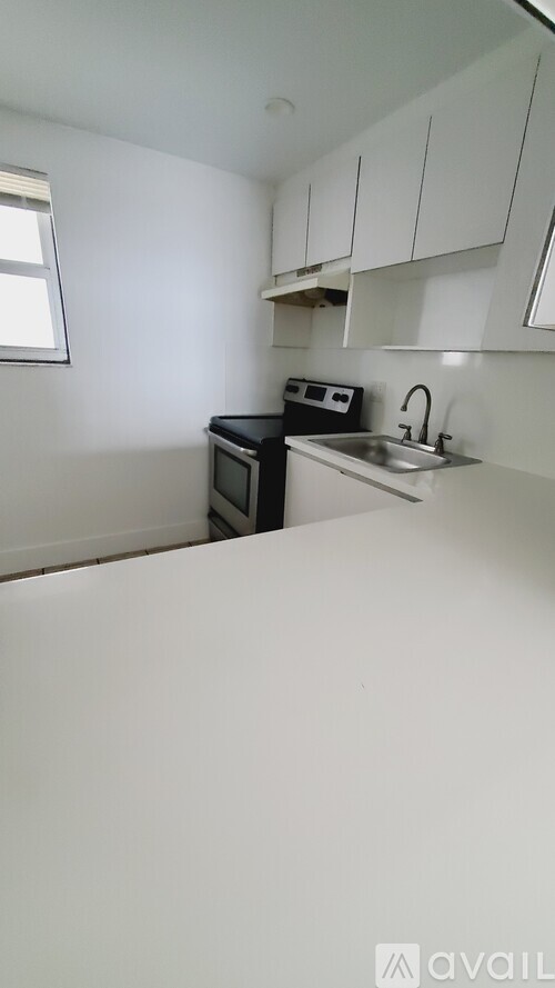 A kitchen with white cabinets and a black microwave.