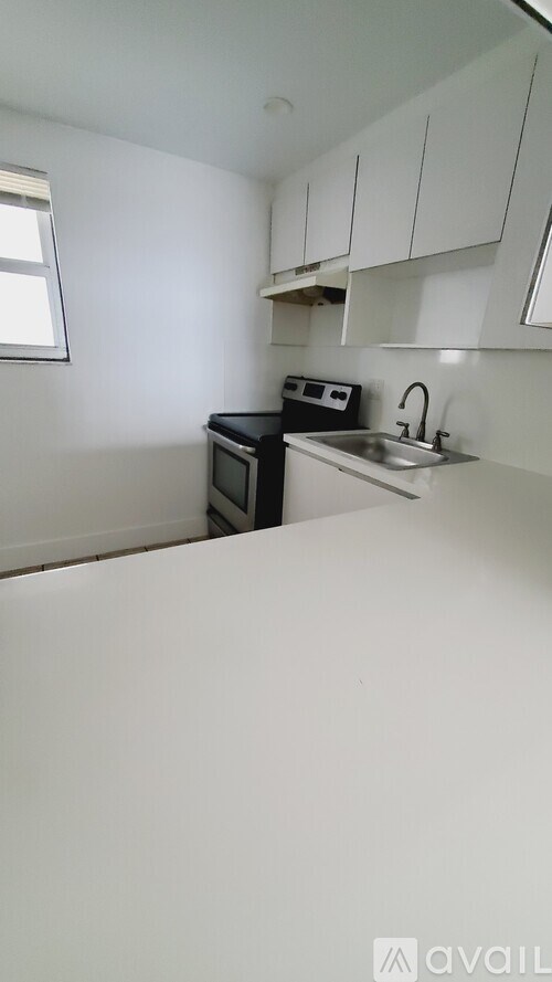 A kitchen with white cabinets and a black microwave.
