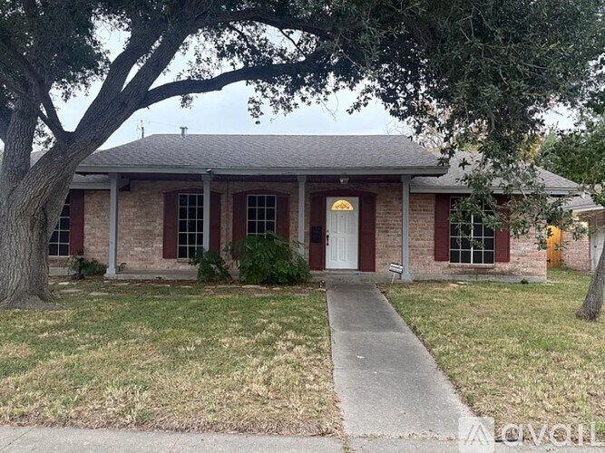 A house with a white door and red shutters is surrounded by trees.