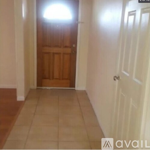 A hallway with a wooden door and a white door on the right.