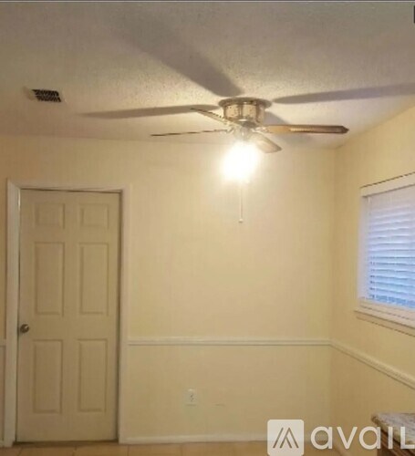 A room with a ceiling fan and a door.