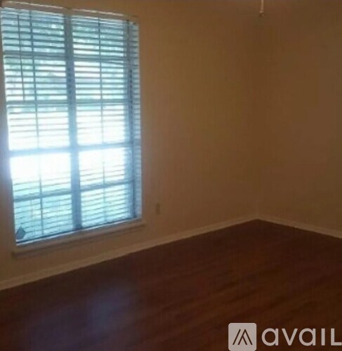 A room with a window covered by white blinds.