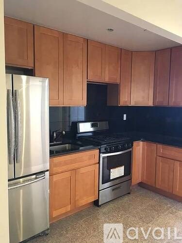 A kitchen with wooden cabinets and a stainless steel refrigerator.
