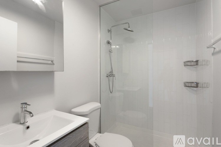 A bathroom with a white sink, toilet, and a glass shower stall.