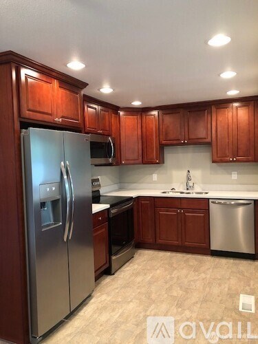 A kitchen with wooden cabinets and a stainless steel refrigerator.