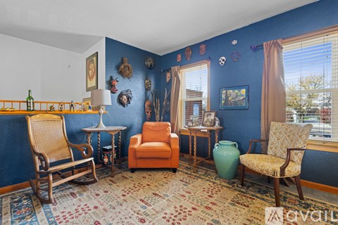 A living room with blue walls and a rug on the floor.