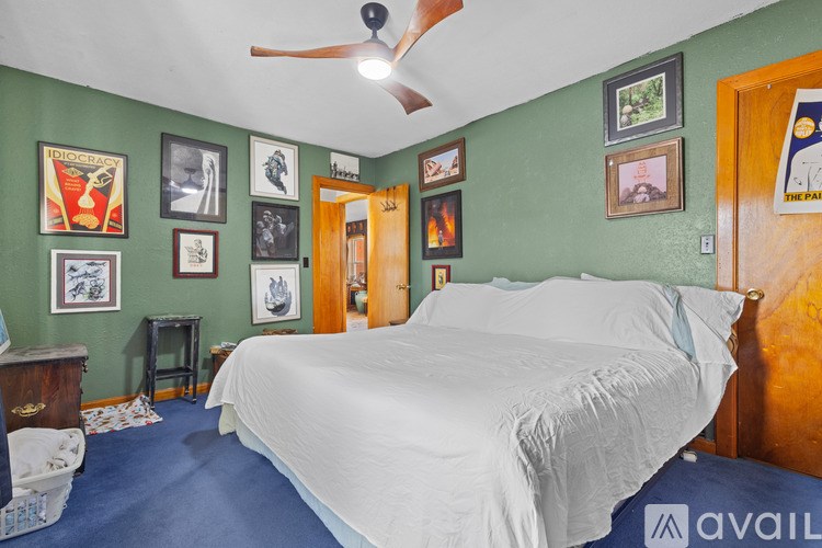 A bedroom with a bed, a ceiling fan, and pictures on the wall.