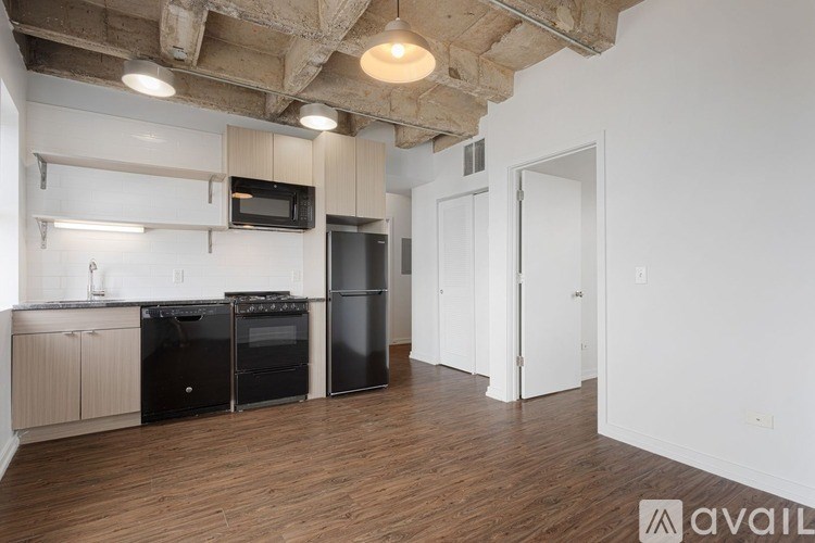 A kitchen with black appliances and wooden floors.