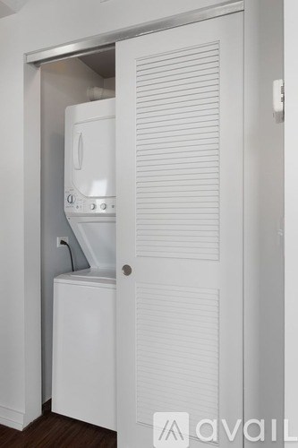 A white washing machine is in a small white closet.