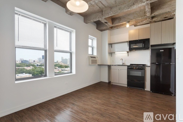 A spacious kitchen with black appliances and wooden floors.