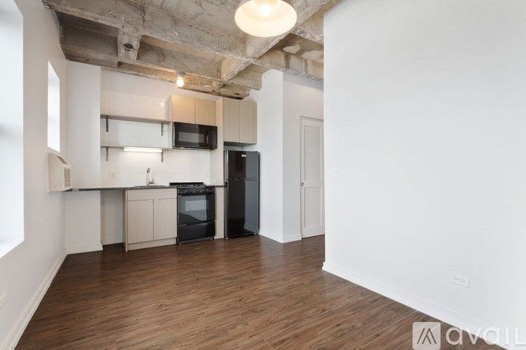 A kitchen with black appliances and wooden floors.