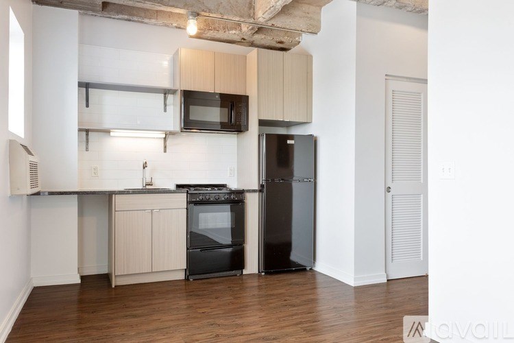 A kitchen with a black refrigerator and white walls.
