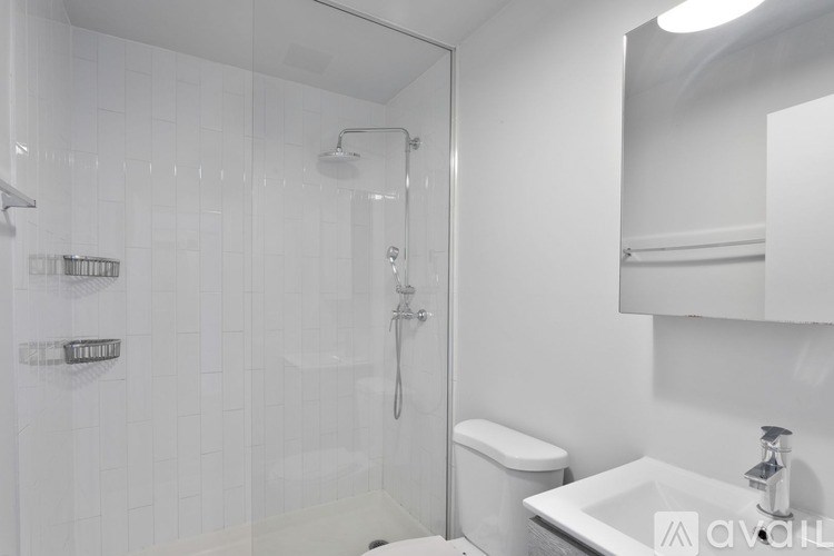 A white bathroom with a glass shower stall and a toilet.