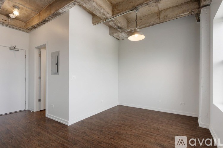 A room with wooden floors and a white wall with a door and a window.