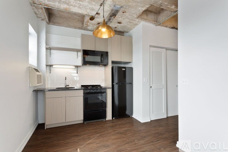 A kitchen with a black fridge and a black stove top.
