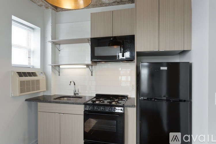 A kitchen with a black refrigerator and a black stove top oven.