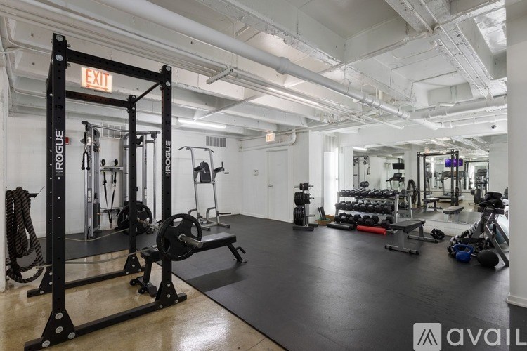 A gym with a variety of equipment including a squat rack, bench, and weights.