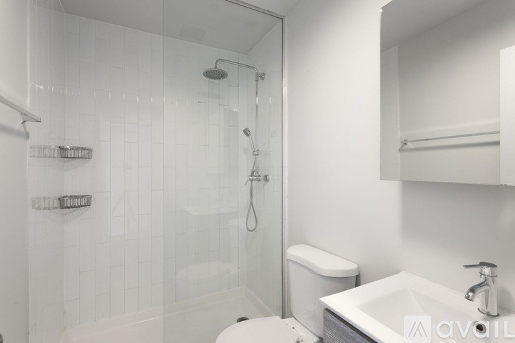 A white bathroom with a toilet, sink, and shower.