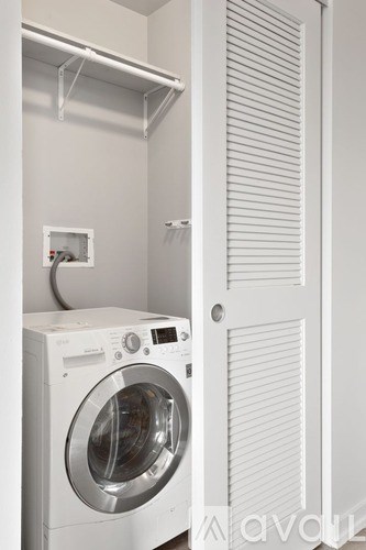 A white washing machine is in a small laundry room.