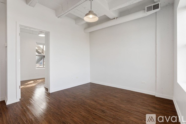 A room with wooden floors and white walls, with a door on the left side.
