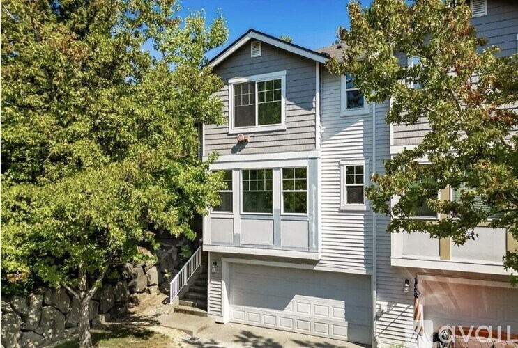 A two-story house with a garage and a tree in front.