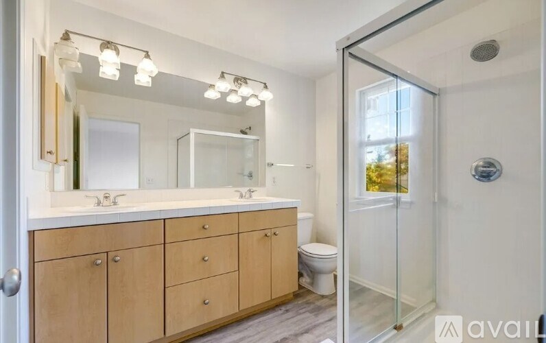 A bathroom with a wooden vanity and a walk-in shower.