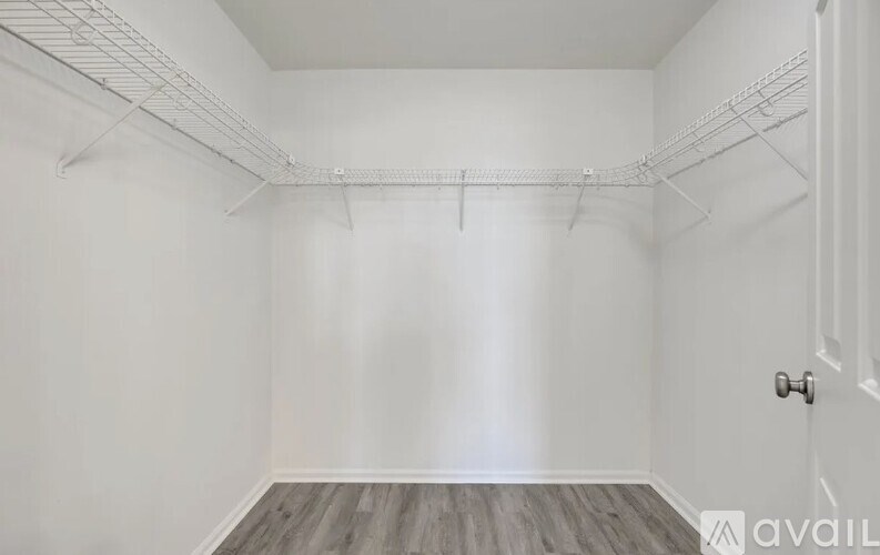A room with a white door and a white wall with a wooden floor.