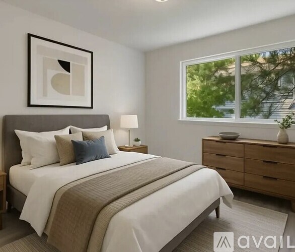 A bedroom with a large bed, a nightstand with a lamp, and a framed picture on the wall.