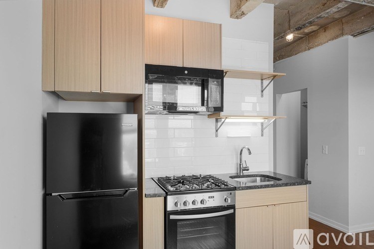 A kitchen with a black refrigerator, stove, and microwave.