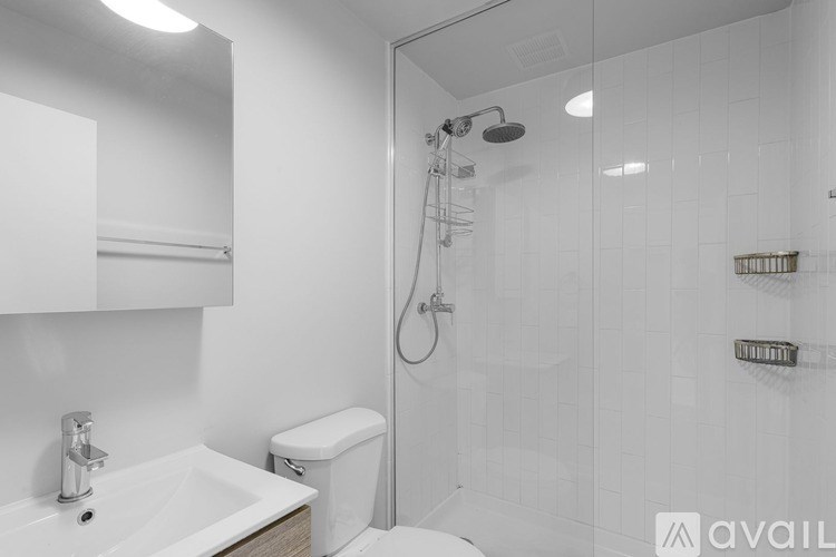 A white bathroom with a sink, toilet, and shower.