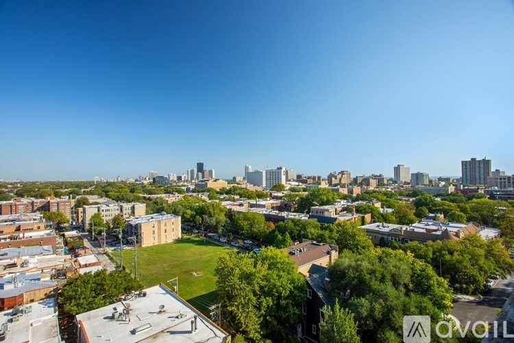 A cityscape with buildings and greenery under a clear blue sky.
