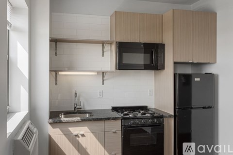 A kitchen with a black fridge and stove top oven.