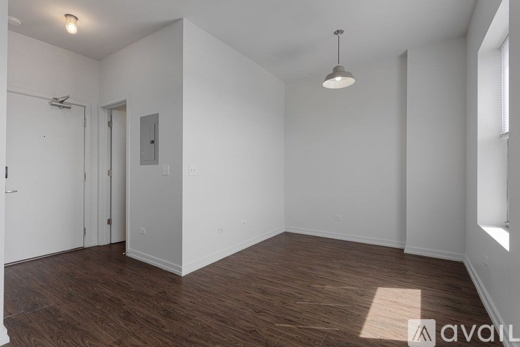 A room with wooden floors and white walls, with a window on the right side.