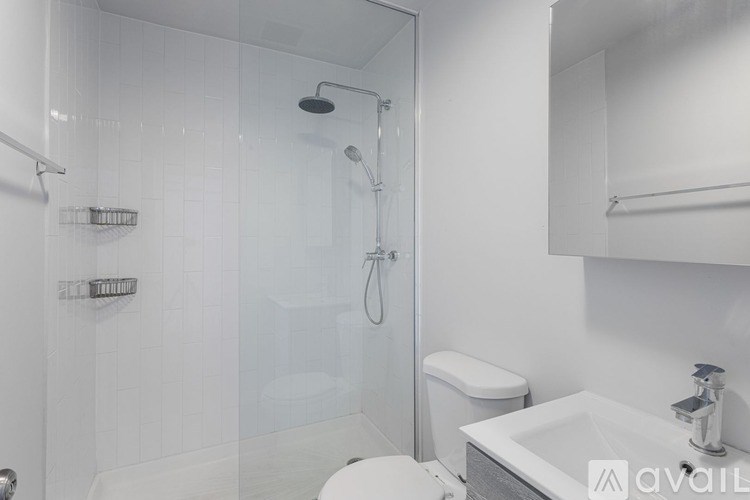 A white bathroom with a glass shower stall and a white toilet.