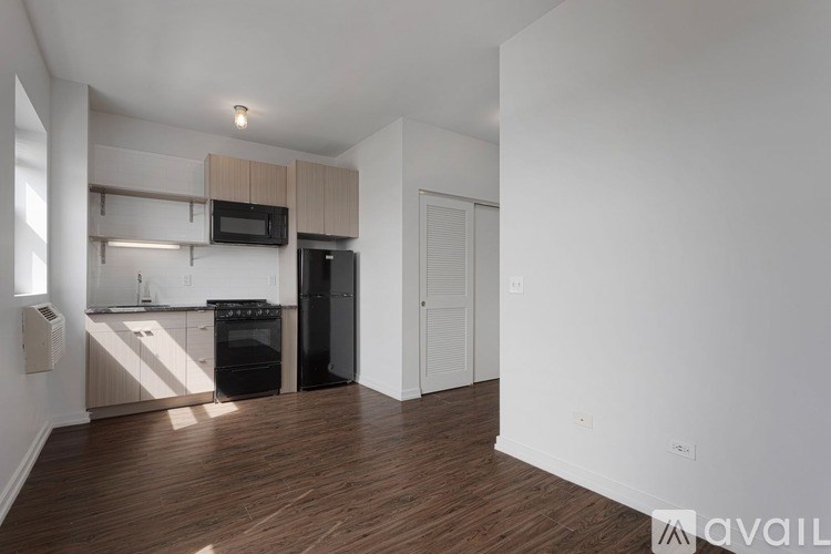 A kitchen with black appliances and wooden floors.