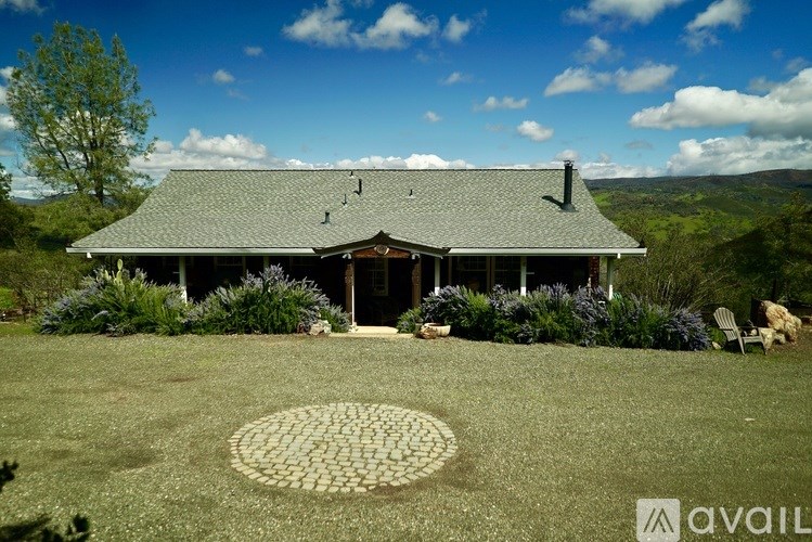 A house with a grey roof and a circular patterned lawn in front.