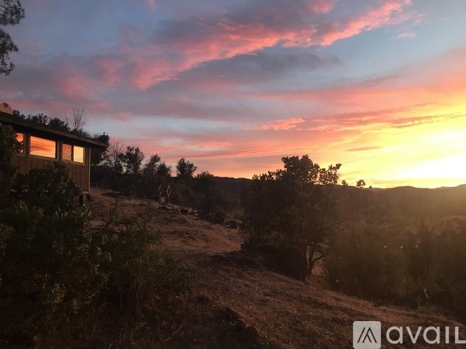 A house is situated on a hill with a beautiful sunset in the background.