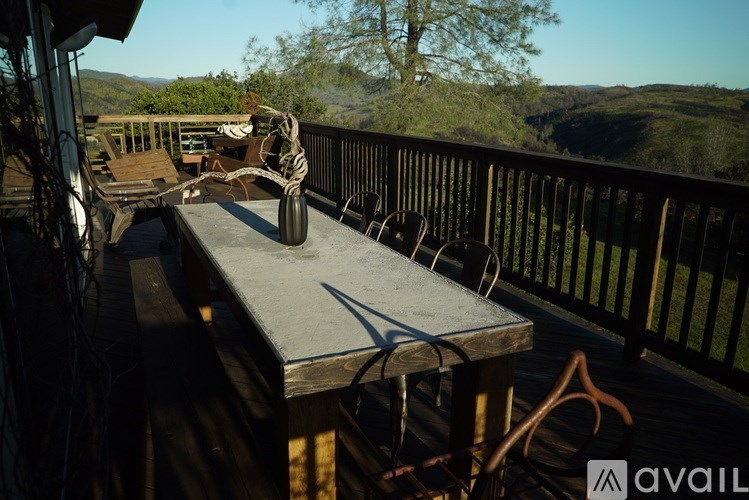 A table with chairs and a rope tied to it on a balcony overlooking a valley.